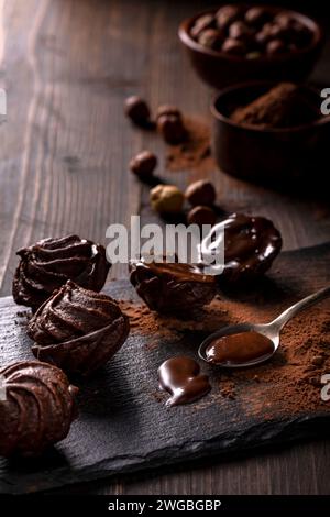 in the foreground, in a dark environment, chocolate kisses with hazelnuts and cocoa powder. Stock Photo