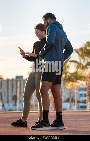 Young athletes using apps on the phone to keep track of their exercise routine.Vertical Stock Photo