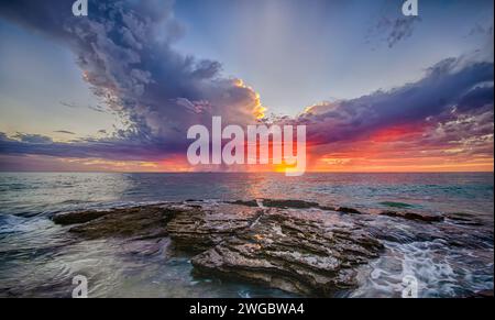 Dramatic sunset over ocean and rocky coastline, Perth, Western Australia, Australia Stock Photo