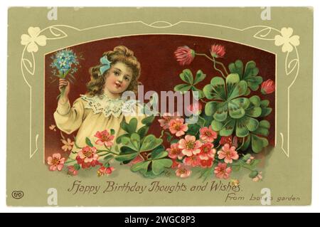 Original early 1900's birthday greetings postcard, of girl, maroon background, with lucky clovers, pink flowers and froget me nots. Published E.A. Schwerdtfeger Co. London. Dated / posted 4 May 1913. Stock Photo