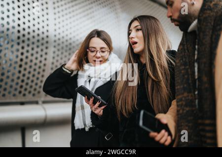 A young, professional team works on a project together outside on a snowy winter day, staying connected with technology. Stock Photo