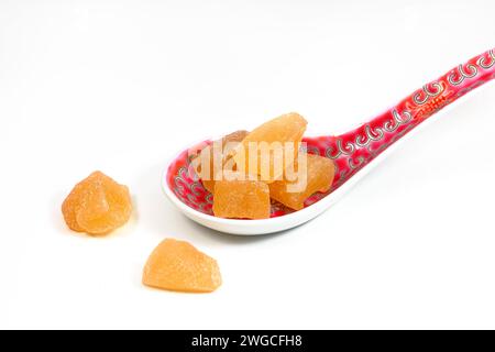 A soup spoon of candied ginger (Zingiber officinale) isolated on a white background. Stock Photo