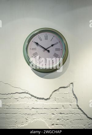 Green Clock with Roman numerals on broken brick wall Stock Photo