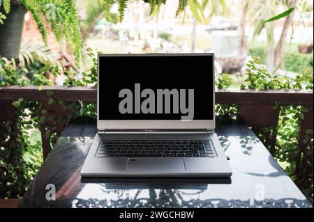 Open modern gray laptop on glass table in spring garden on sunny Stock Photo