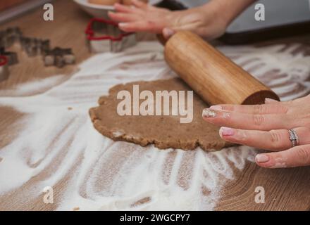 Close-up photo of hands using rolling pin on cookie dough for gingerbread cookies Stock Photo