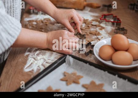 Close up of hands cutting christmas cookies with cookie cutters and arranging them on baking tray Stock Photo