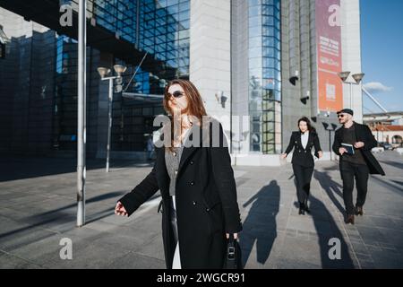 Three young business entrepreneurs or colleagues in casual attire collaborating while walking together in a modern cityscape. Stock Photo