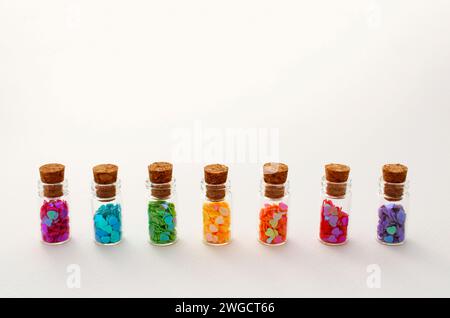Glass bottles arranged in a row each containing hearts of different colors Stock Photo