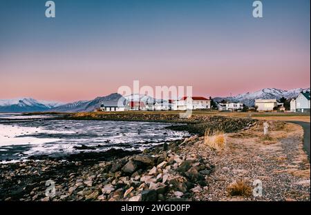 A little village with typical Nordic houses in the southern of Iceland with mountains and snow in the background during sunset Stock Photo