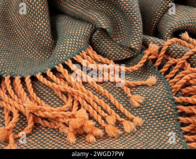 Orange fringe on the edge of the woven garment, selective focus. Textured fabric, close up Stock Photo