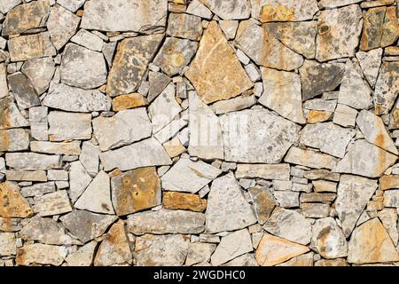 Yellow and grey rocks arranged in an outdoor wall-like structure Stock Photo