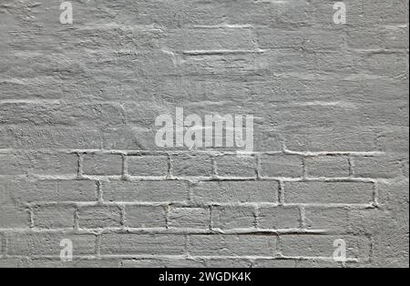 Grey building wall, painted with whiting. Wavy and bumpy surface. Brick wall and its texture in gray old-style color. Uneven brickwork Stock Photo
