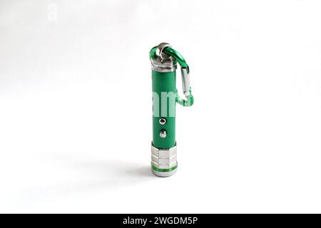 A laser pointer with a green metal body stands vertically on the table surface. Stock Photo