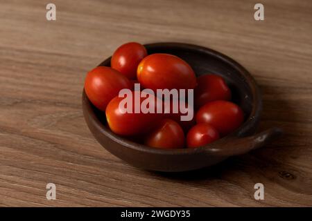 plum tomatoes in a clay dish on the table Stock Photo