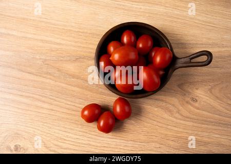 plum tomatoes in a clay dish on the table seen from the top Stock Photo