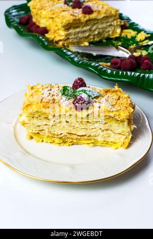 A piece of dessert Napolen garnished with raspberries for consumption on the table Stock Photo