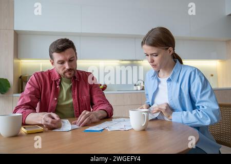 Thoughtful couple planning family budget, analysing, counting expenses on smartphone calculator Stock Photo