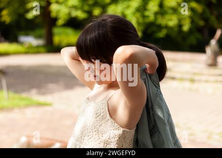 Young woman suffering from backache in the park on a summer day Stock Photo