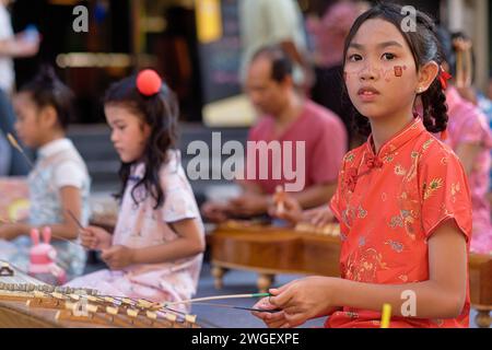 Thai children playing classical Thai music, lead by 3 young girls playing the khim, a string instrument akin to a dulcimer; in Phuket, Thailand Stock Photo