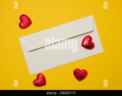 Rectangular white paper envelope and red hearts on a yellow background, holiday background Stock Photo