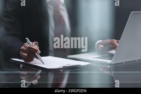 uses a laptop on a wooden table in a dark room. Stock Photo