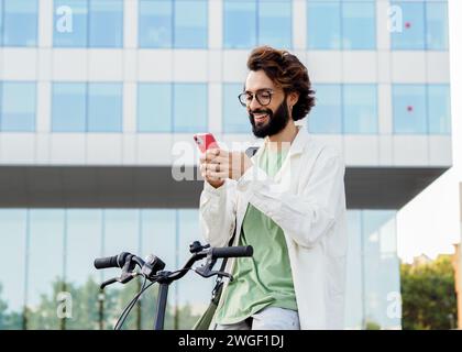 Millennial businessman chatting on smartphone with a bike in a city Stock Photo