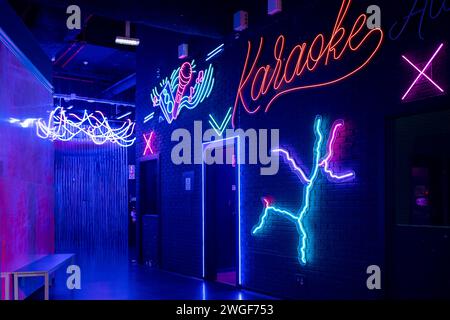 Glowing neon sign with word Karaoke and microphone mounted on brick wall, setting the scene for Karaoke night at illuminated arcade. Entertainment concept. Stock Photo