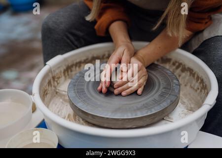 Close up woman doing pottery on pottery wheel. Child creative activities and art. Boy making pottery with mom, having fun. Happy family moment. Stock Photo