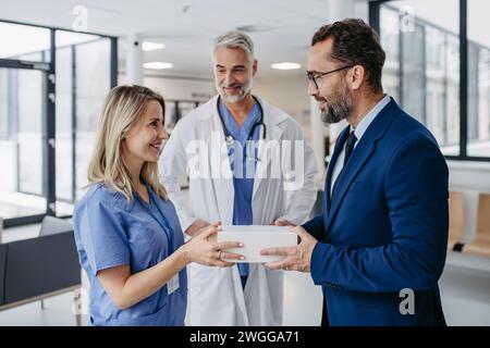 Pharmaceutical sales representative presenting new product to doctors in holding box with pills. Presenting new pharmaceutical product, drugs Stock Photo
