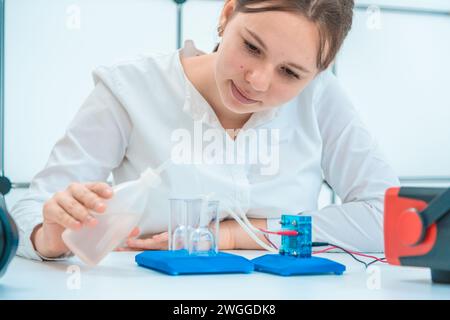 Fuel Experiments young female student conducting experiments with hydrogen fuel cell in ...