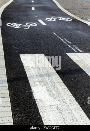 From above of empty asphalt road with white boundary lines and pedestrians zebra crossing markings while bicycle image impressions painted on black Stock Photo
