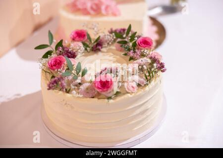 Wedding cake with red marzipan roses on the wedding table. Stock Photo