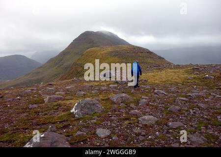 Man (Hiker) Walking on the Ridge to the Summit of the Scottish Mountain Corbett 'Beinn an Eoin' Flowerdale Forest, Wester Ross, North West Highlands. Stock Photo