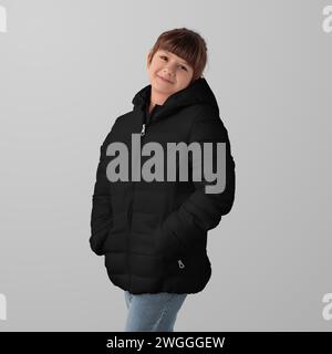 Mockup of a black winter puffer jacket on a child, garment zippers up, hands in pockets, front view, space for design, branding. Template fashionable Stock Photo