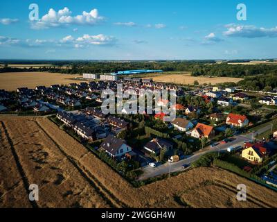 Residential houses in small town near agricultural field, bird eye view. Aerial view of European suburban neighborhood with townhouses. Real estate in Stock Photo