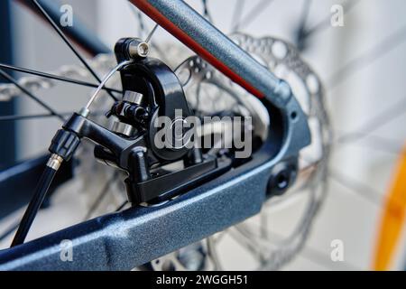 Part of the bicycle's braking system. Grey metal brake disc and brake pads on road bike, close up. Stock Photo