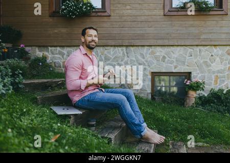 Low angle shot of man working outdoors in the garden, eating lunch, sandwich. Businessman working remotely from homeoffice, thinking about new Stock Photo