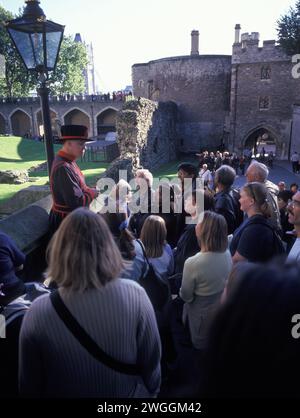 UK, London, a Beefeater giving a guided tour of the Tower of London grounds. Stock Photo