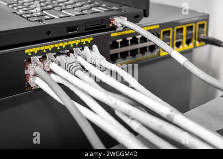 Network Gigabit Smart PoE Switch with laptop connected network cables getting configured on the desk with a laptop Stock Photo