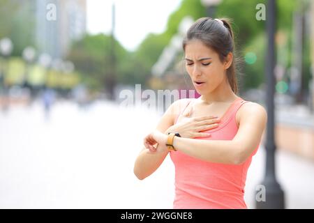 Tired runner checking time on smartwatch after running in the street Stock Photo