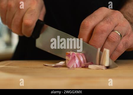 Married man slicing shallots on wooden cutting board Stock Photo