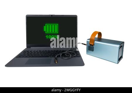 Laptop next to a power bank with a USB cable, on a white background. On laptop screen there is a green indicator of 100% battery charge (full charge) Stock Photo