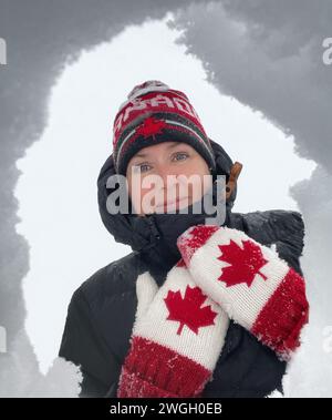 Woman wearing Canada hat and mittens looking down into snow in winter. Stock Photo