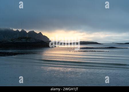 Sunbeams breaking through misty clouds over mountain range Stock Photo