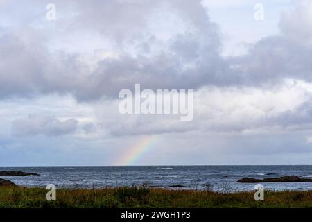 Rainbow above ocean on cloudy day Stock Photo