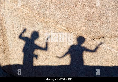 children playing with shadows on a rock in Joshua Tree National park Stock Photo