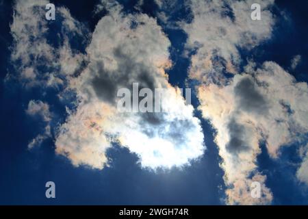 Looking straight up at a triangular cloud blocking the sun overhead, creating dramatic shadows and a bright silver lining Stock Photo