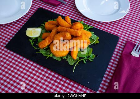 Sepia in a batter of tempera flour with lemon and arugula Stock Photo ...