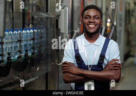 Young successful African American inspector in workwear looking at camera with smile while standing by industrial equipment Stock Photo