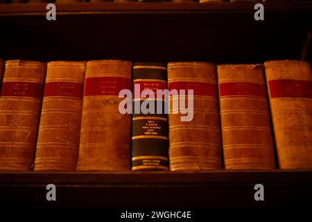 Vintage hardcover French law books with gold lettering on a dark wooden bookshelf, conveying a classic library atmosphere. Stock Photo